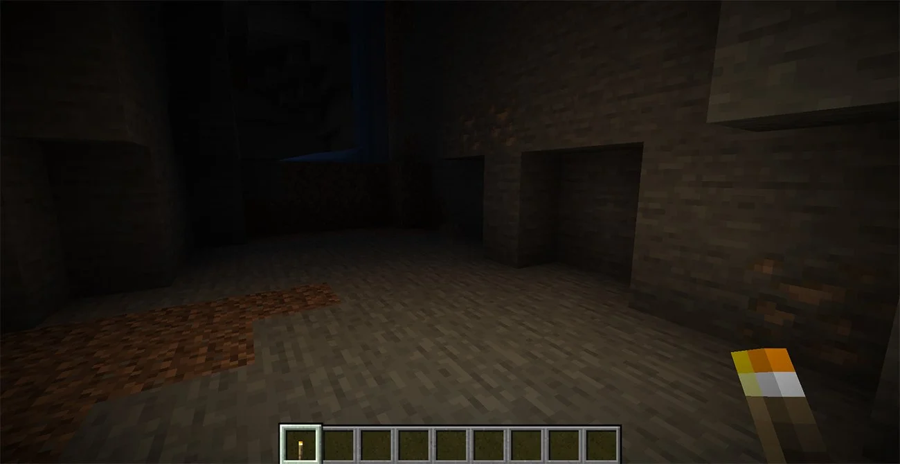 Minecraft cave lit by a handheld torch